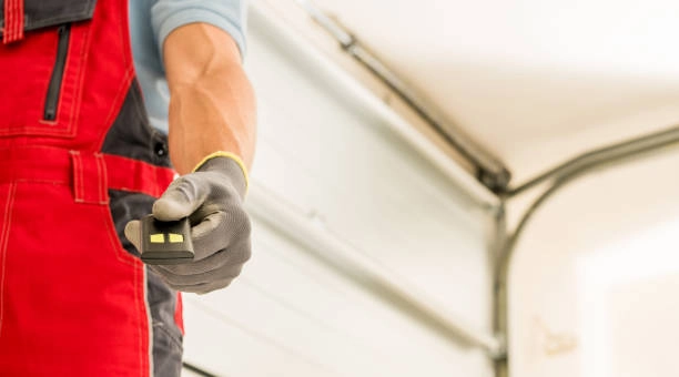 person holding a remote wearing red bottoms and garage door behind -garage door installer